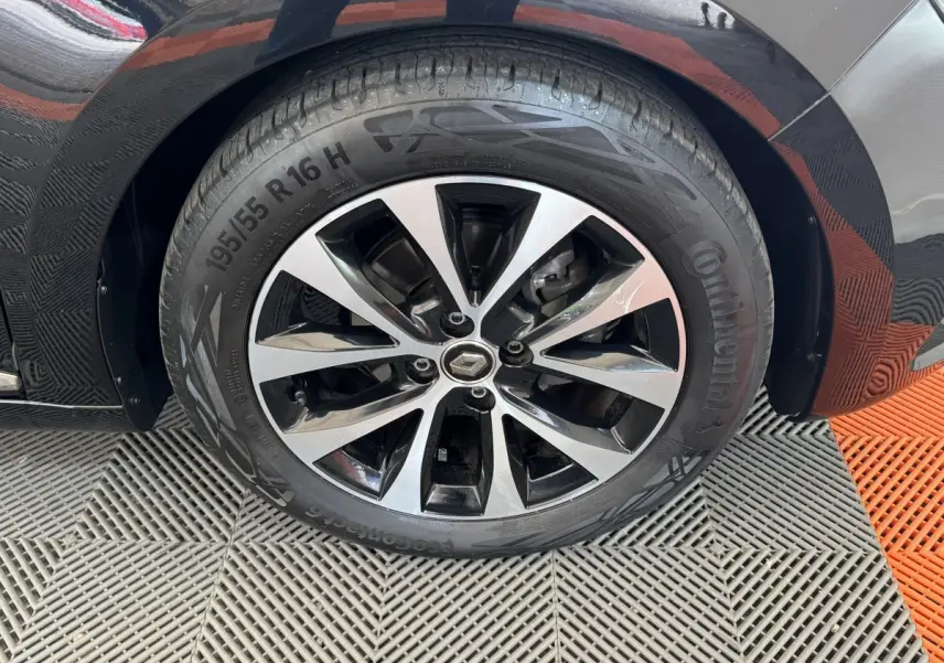 Gros plan sur la roue avant gauche noire de la Renault Clio Intens TCe 100 avec jante alliage bicolore.