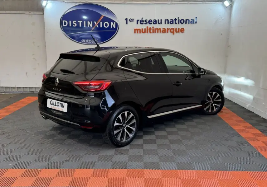 Renault Clio Intens TCe 100 noire vue en 3/4 arrière droit dans un showroom avec sol gris et bandes orange.