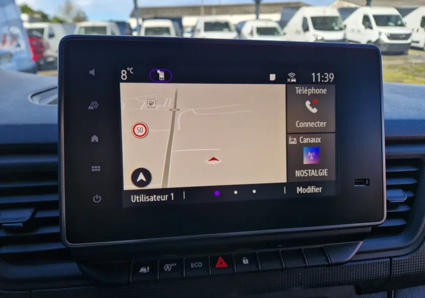 Vue intérieure centrée sur l'écran tactile Easy Link 8'' du Renault Trafic blanc, affichant la navigation et options connectées.