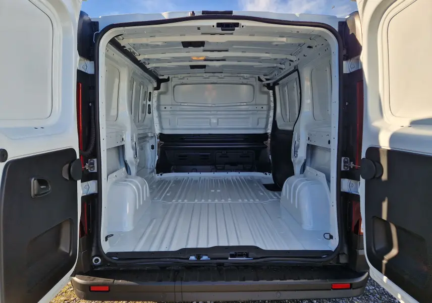 Vue arrière ouverte du Renault Trafic Fourgon blanc 2025, montrant l’espace de chargement vide et la structure intérieure métallique.