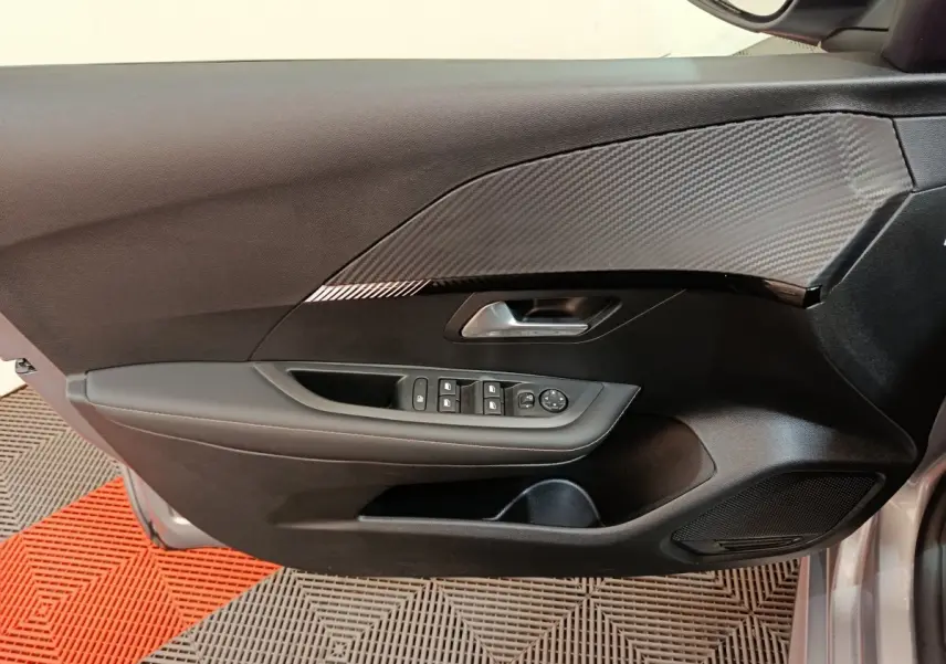 Vue intérieure de la porte avant gauche gris clair de la Peugeot 208 PureTech 100 S&S Allure avec commandes électriques et insert carbone.