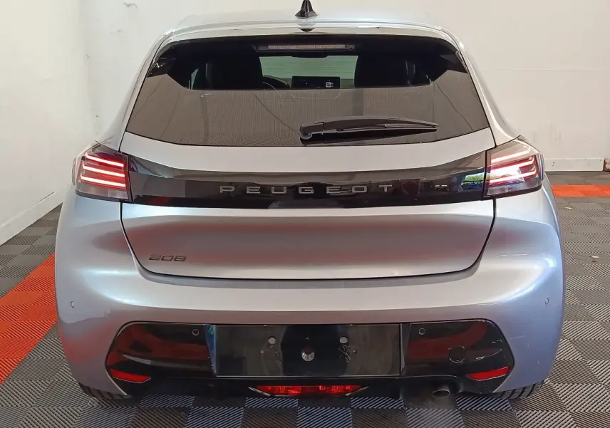Vue arrière d'une Peugeot 208 gris clair 2025 avec feux LED et logo Peugeot lumineux sur la malle.