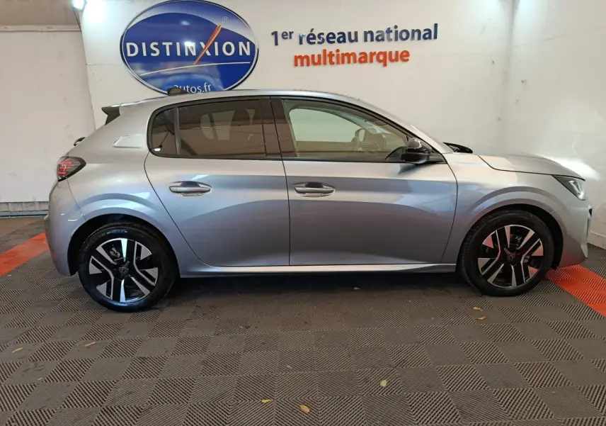 Profil côté droit d'une Peugeot 208 PureTech 100 S&S Allure gris clair, avec jantes noires et vitres teintées.