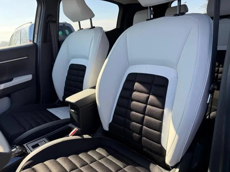 Gros plan sur les sièges avant bicolores noir et gris du Citroën C3 Aircross 2026, avec accoudoir central visible.