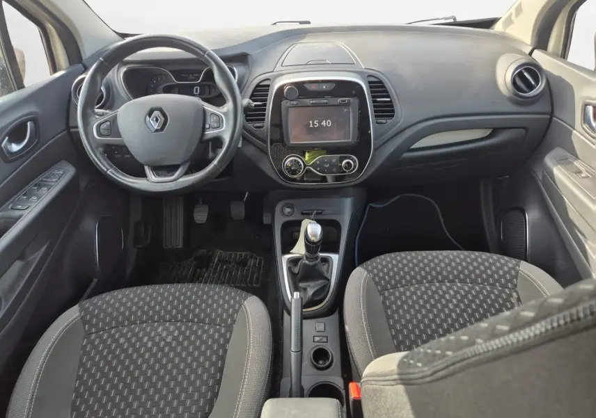Vue intérieure avant du Renault Captur 2018 montrant le tableau de bord noir, volant multifonction et levier de vitesse manuel.