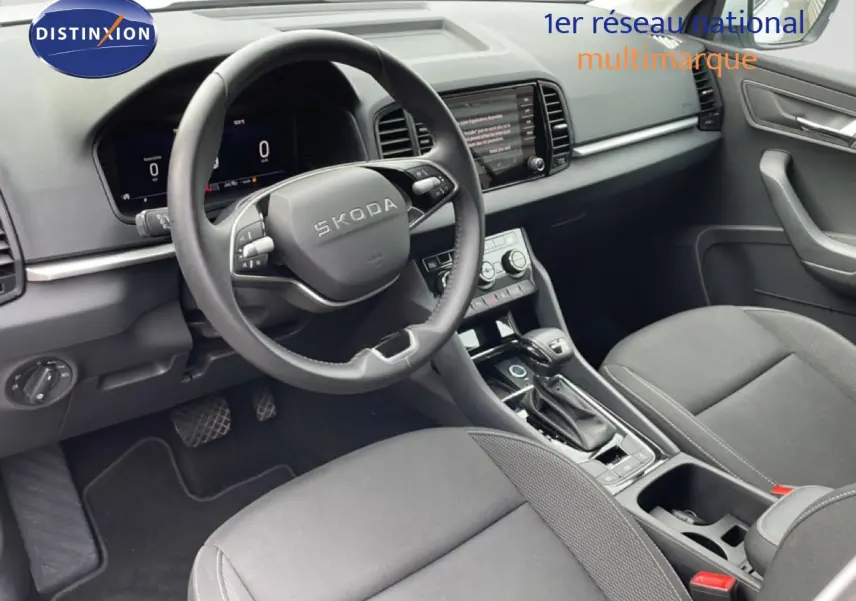 Intérieur noir du Skoda Karoq 2025 vu côté conducteur, volant multifonction et console centrale avec écran tactile.