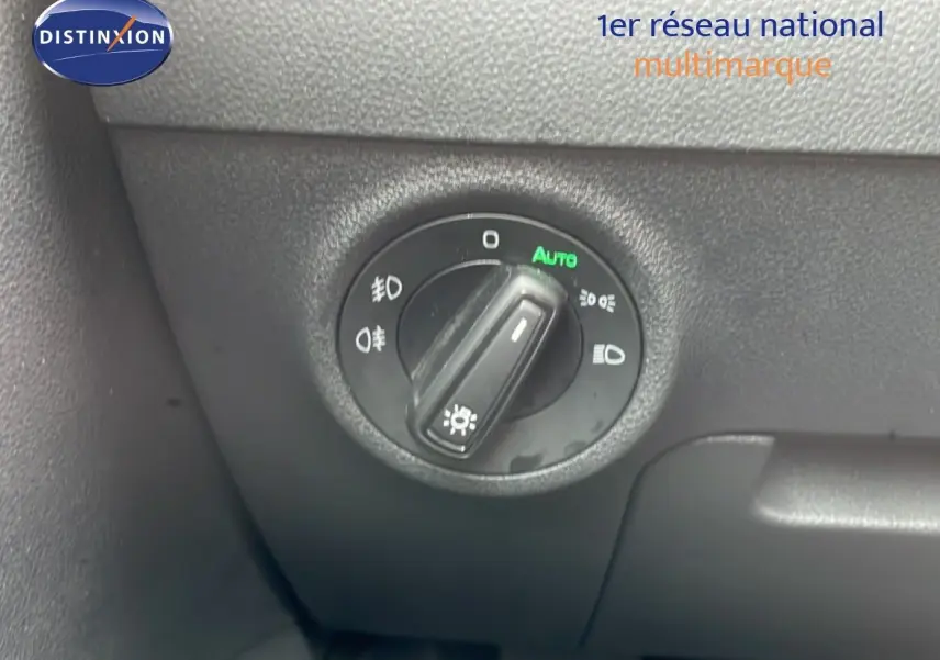 Gros plan sur le bouton de commande des phares du Skoda Karoq blanc glacier, intérieur côté gauche.