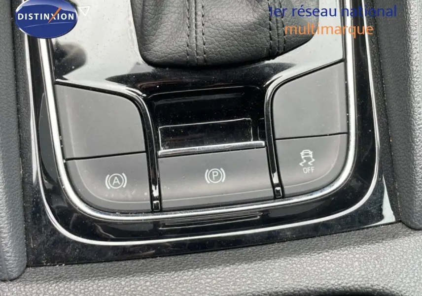 Gros plan sur la console centrale noire brillante du Skoda Karoq blanc glacier, montrant les boutons de contrôle électroniques.