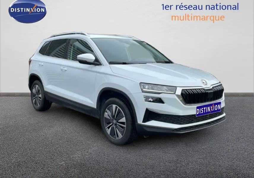 SUV SKODA KAROQ blanc glacier en 3/4 avant droit, avec calandre noire et jantes bi-ton distinctives.