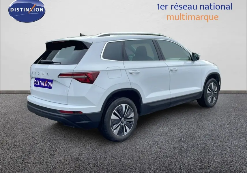 Vue 3/4 arrière droite d'un Skoda Karoq blanc glacier 2025 avec jantes bi-ton et feux arrière LED distinctifs.