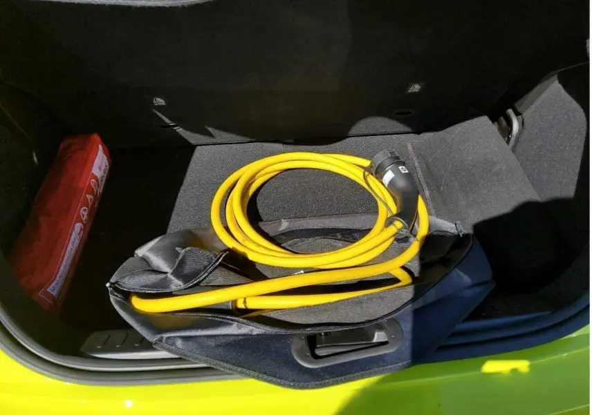 Coffre ouvert d’une FIAT 500 Electrique Jaune Acid avec câble de recharge jaune enroulé visible.