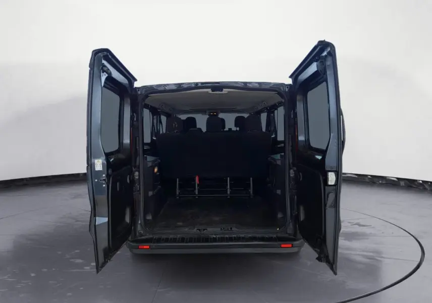 Vue arrière du Renault Trafic Combi gris foncé métal avec portes ouvertes dévoilant l'espace intérieur et les sièges passagers.