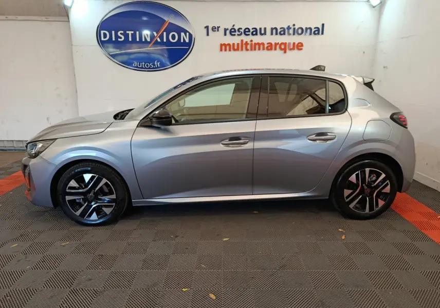 Profil latéral droit d'une Peugeot 208 PureTech 100 S&S Allure gris clair, avec jantes alliage et vitres teintées.