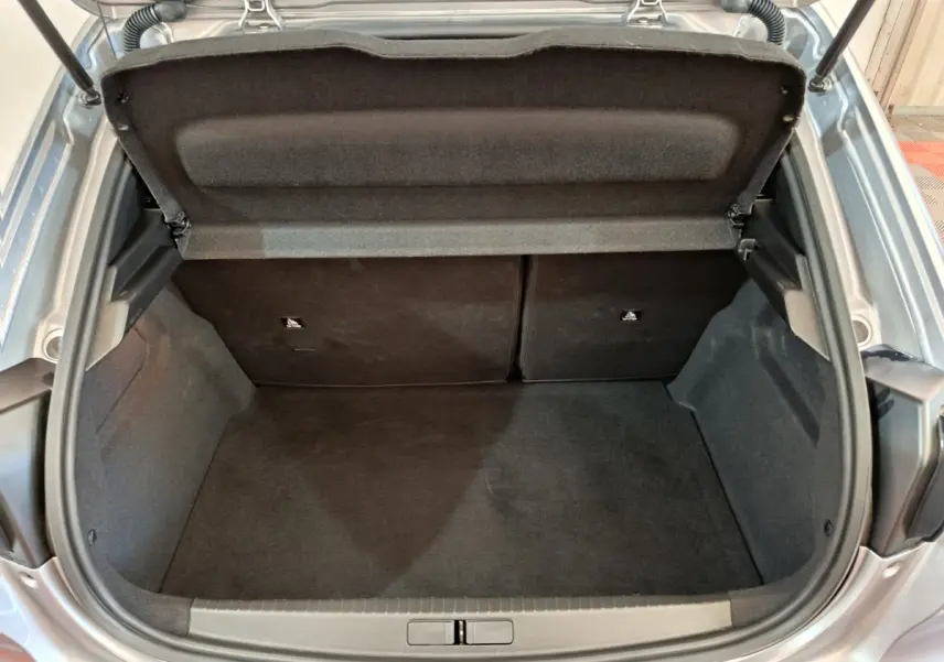 Coffre ouvert vu de dessus d'une Peugeot 208 gris clair, montrant l'espace de chargement et la tablette arrière.