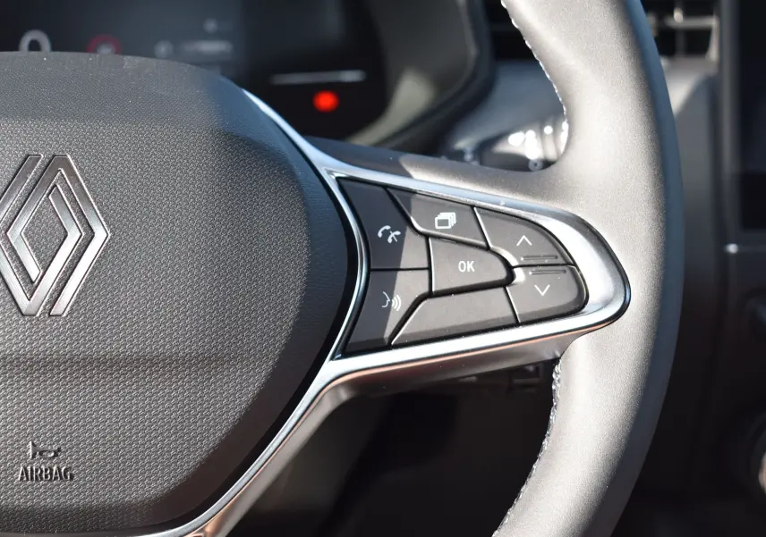 Gros plan sur la partie droite du volant noir de la Renault Clio V 2025, avec commandes multifonctions et logo Renault visible.