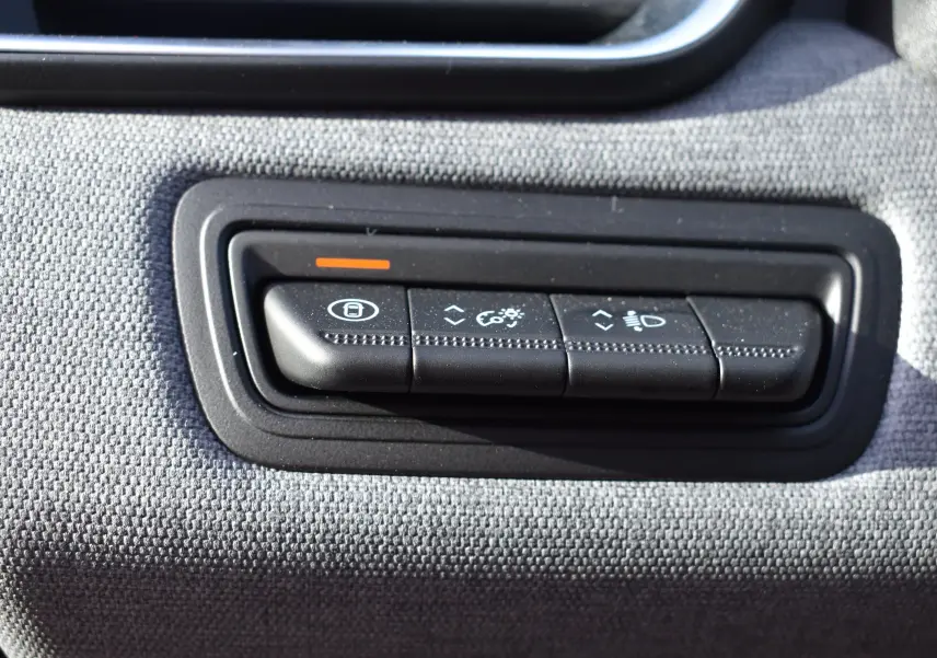 Gros plan sur les boutons de réglage d’éclairage et verrouillage de la Renault Clio V TCe 90 noire, intérieur tissu gris.