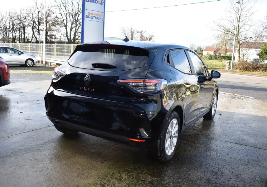 Vue 3/4 arrière droite d'une Renault Clio V noire 5 portes, avec feux arrière LED et jantes argentées, stationnée en extérieur.