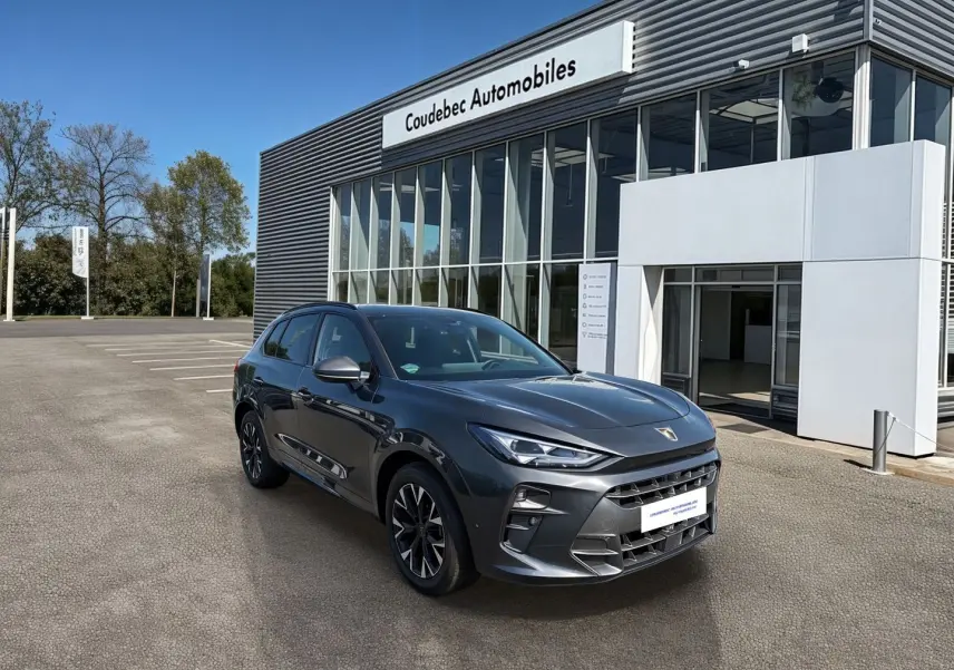 CUPRA TERRAMAR gris en 3/4 avant droit, avec jantes 18'' anthracites et calandre imposante devant un concessionnaire.