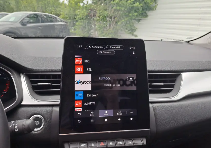 Écran tactile central du tableau de bord du Renault Captur 2024, affichant les stations radio avec commandes en dessous.