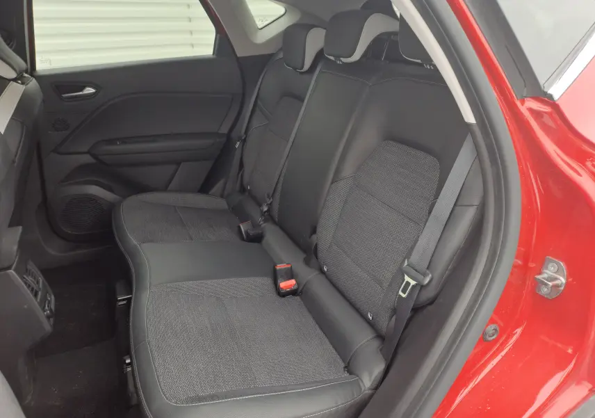 Vue intérieure du siège arrière droit du Renault Captur rouge flamme métal 2024 avec sellerie noire mixte cuir et tissu.