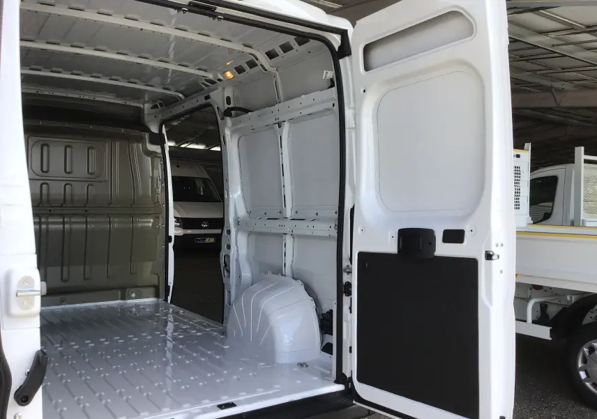 Vue intérieure arrière du Peugeot Boxer Fourgon blanc 2025, montrant l'espace de chargement vide et les portes ouvertes.