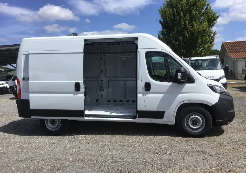 Peugeot Boxer Fourgon blanc vu de profil droit avec porte latérale coulissante ouverte montrant l'intérieur vide.