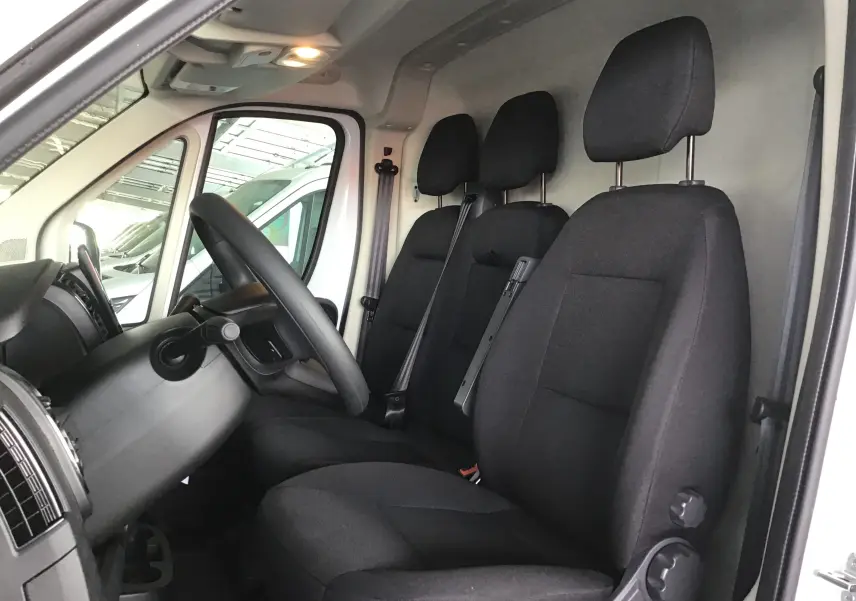 Intérieur du Peugeot Boxer Fourgon blanc 2025, vue côté gauche sur les sièges noirs et le volant.