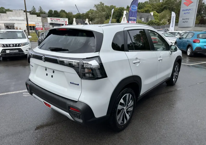 Suzuki S-Cross blanc 2025 en 3/4 arrière droit, avec feux arrière fumés et jantes alliage visibles.