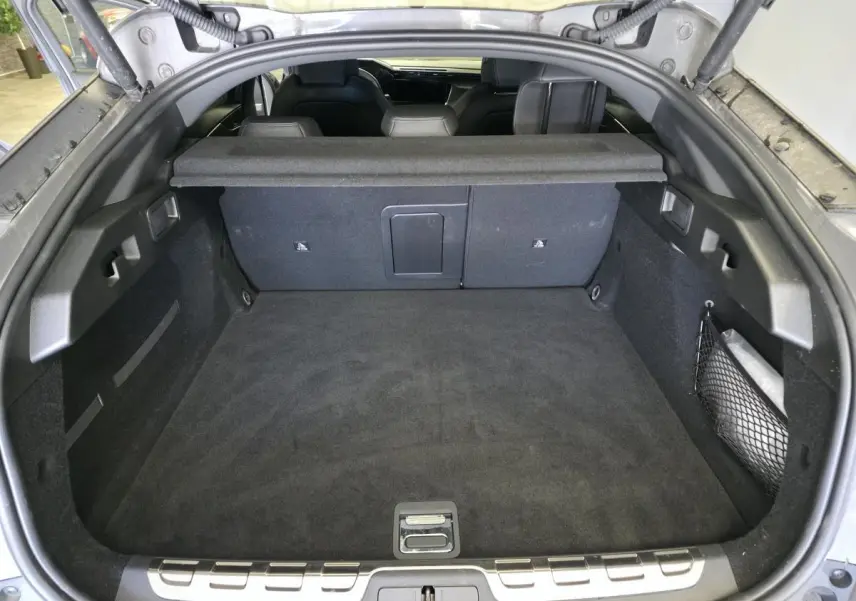 Coffre ouvert vu de l'arrière d'une Peugeot 408 gris, avec banquette arrière et filet de rangement latéral visibles.