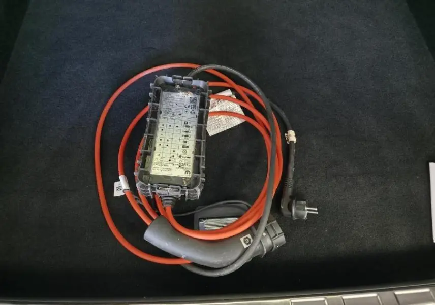 Gros plan sur câble de recharge orange et noir dans le coffre d'une Peugeot 408 gris Selenium 2025 hybride rechargeable.