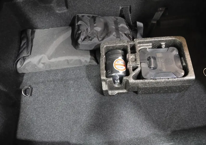 Vue intérieure du coffre noir de la BMW Série 2 Active Tourer 216d avec rangement en mousse et accessoires rangés.
