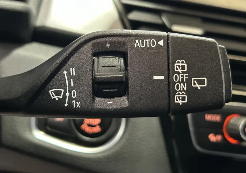 Gros plan sur la commande de l’essuie-glace intérieur noir dans l’habitacle d’une BMW Série 2 Active Tourer blanche.