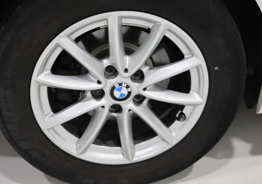 Gros plan sur la jante alliage argentée d'une BMW Série 2 Active Tourer blanche, avec logo BMW au centre.