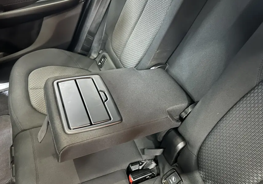 Détail de l'accoudoir central arrière en tissu gris dans l'habitacle d'une BMW Série 2 Active Tourer blanche.