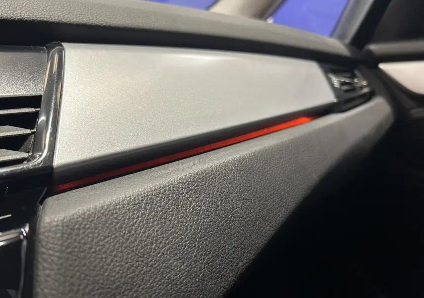 Détail intérieur côté passager de la BMW Série 2 Active Tourer 216d 2021, avec bande décorative rouge et finition noire texturée.