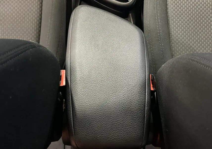 Vue rapprochée de l'accoudoir central en cuir noir entre les sièges avant en tissu d'une BMW Série 2 Active Tourer blanche.