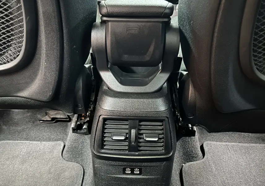 Vue rapprochée de la console arrière noire entre les sièges avant d’une BMW Série 2 Active Tourer blanche.