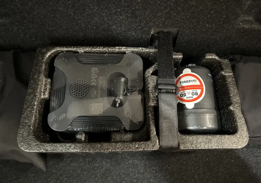 Kit de réparation de pneu avec compresseur et produit d'étanchéité dans le coffre d'une BMW Série 2 Active Tourer blanche.