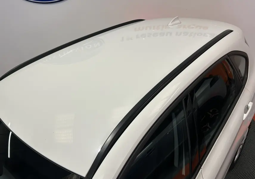 Vue plongeante sur le toit blanc et le côté droit d'une BMW Série 2 Active Tourer 216d avec antenne requin et barres de toit noires.