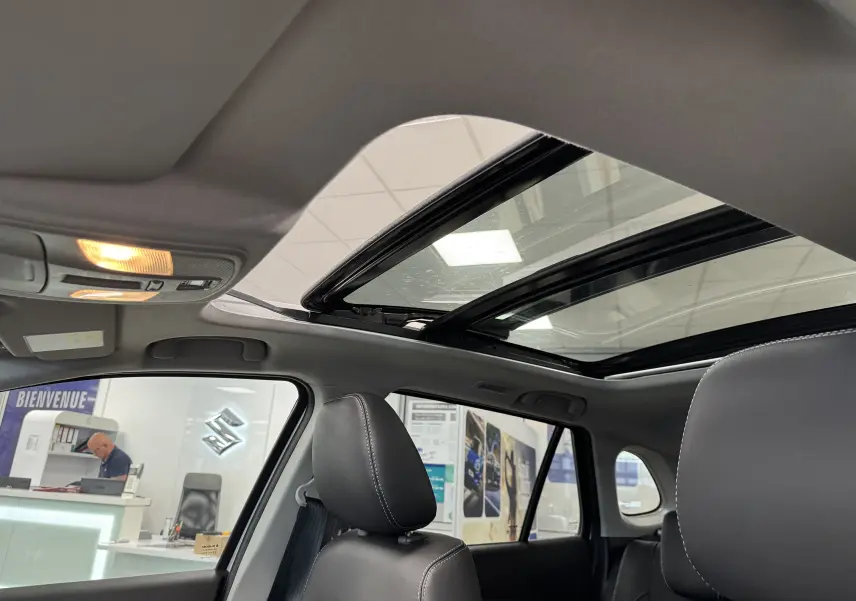 Intérieur du Suzuki S-Cross 1.4 gris 2025, vue sur toit panoramique ouvrant et sièges en cuir noir.