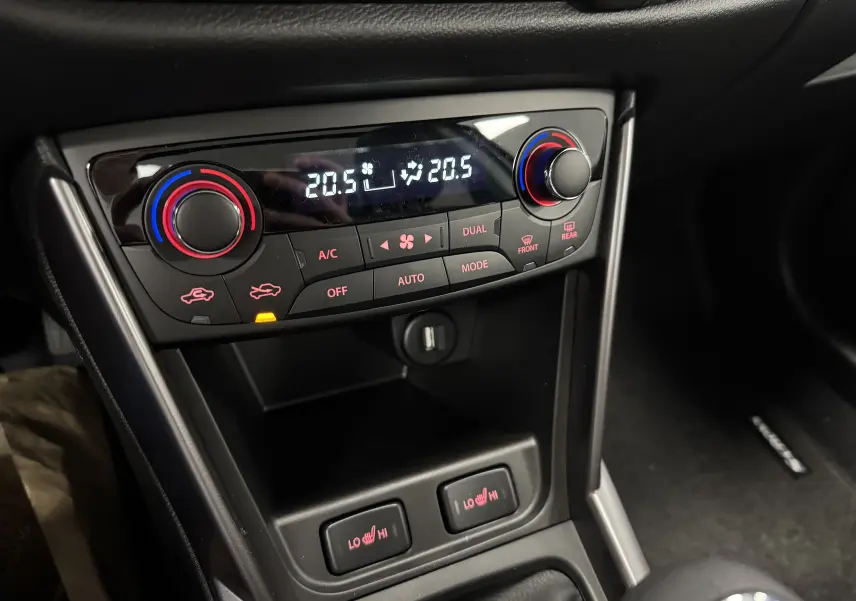 Vue rapprochée de la console centrale du Suzuki S-Cross 2025 gris, montrant la climatisation automatique et les commandes des sièges chauffants.