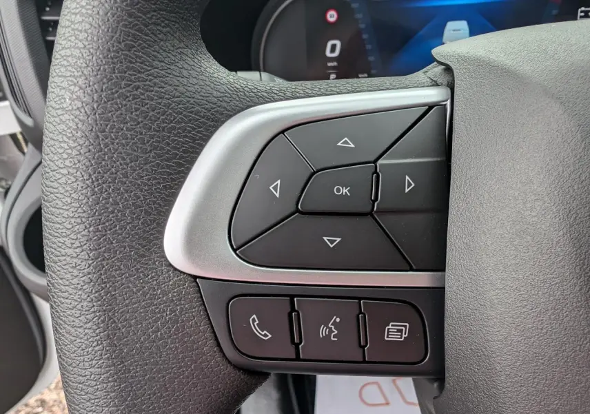 Gros plan sur les commandes multifonctions du volant du Iveco Daily blanc, avec boutons directionnels et appels.
