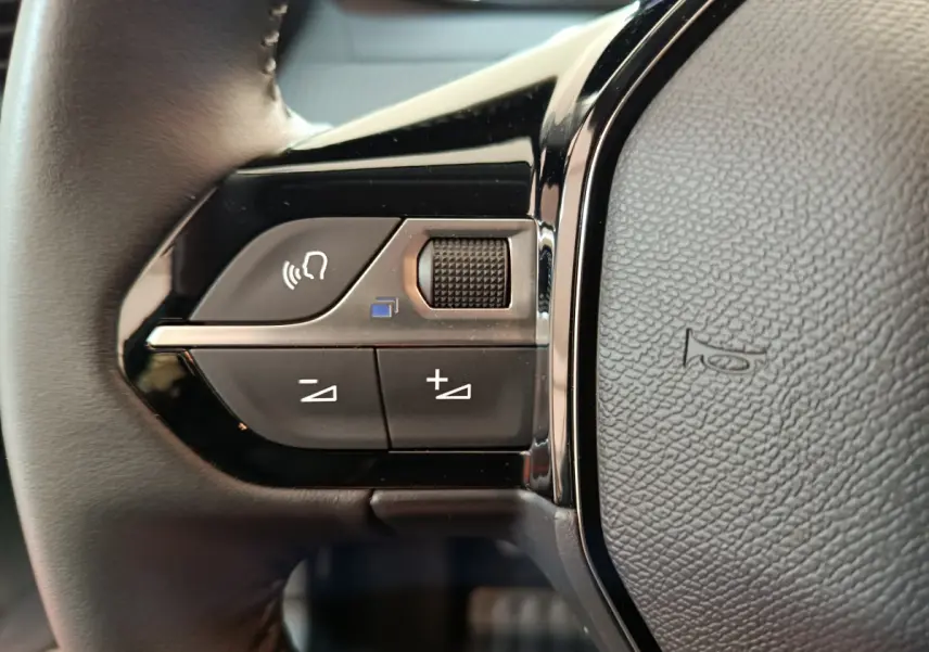 Gros plan sur les commandes du volant cuir côté gauche de la Peugeot 208 PureTech 100 S&S Allure 2025.