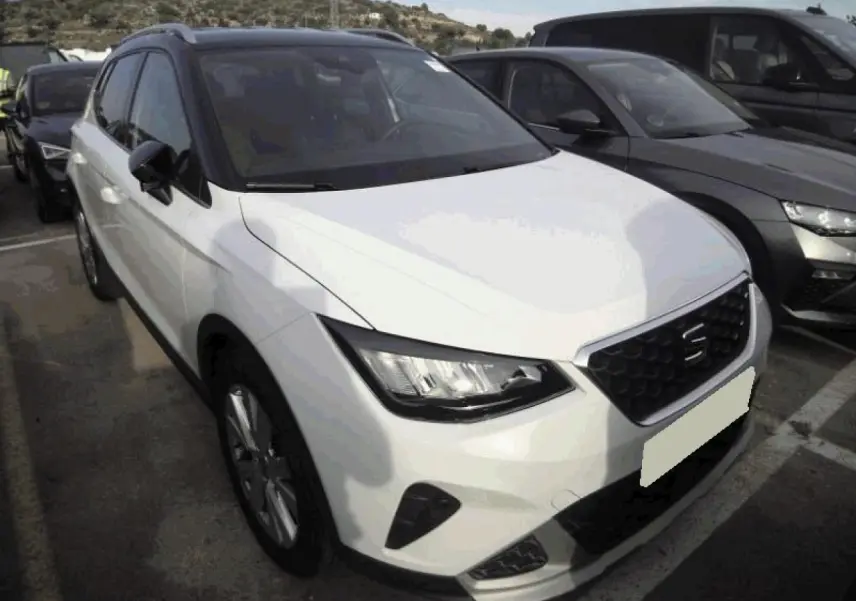 SEAT Arona blanc Nevada en vue 3/4 avant, toit noir contrasté et calandre chromée XPERIENCE visible.