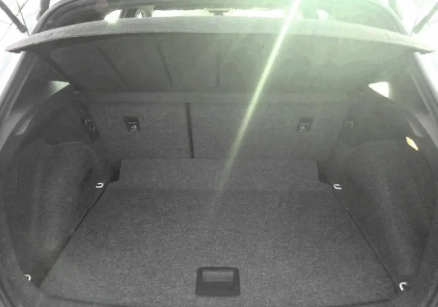 Vue intérieure du coffre spacieux et vide du SEAT ARONA blanc Nevada, avec hayon ouvert vers le haut.