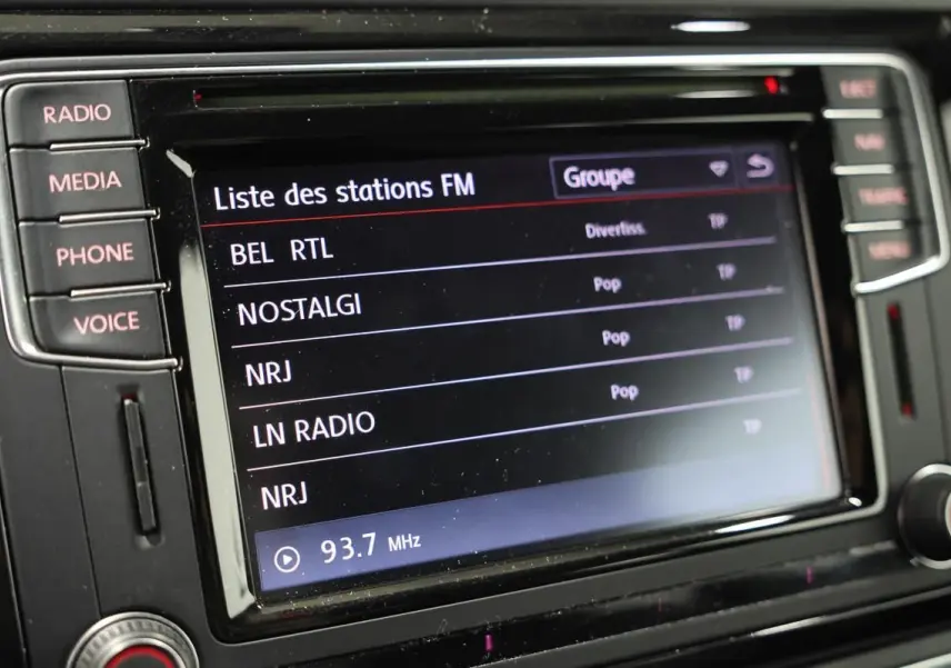Gros plan sur l’écran central tactile du GPS de la Volkswagen Coccinelle gris, affichant la liste des stations FM.
