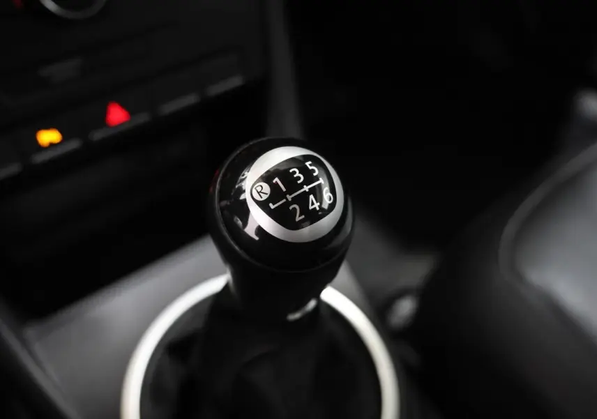 Le levier de vitesse manuel noir de la Volkswagen Coccinelle 1.2 TFSI 105, vue rapprochée de l'intérieur.