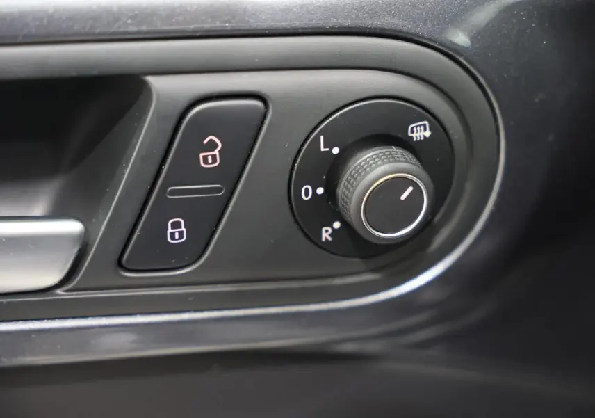 Gros plan sur les commandes de réglage des rétroviseurs et verrouillage sur la porte intérieure d'une Volkswagen Coccinelle grise.