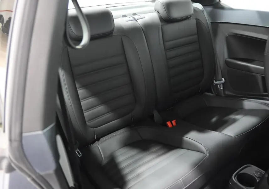 Vue intérieure des sièges arrière en cuir noir de la Volkswagen Coccinelle gris 2016, avec ceinture de sécurité visible.