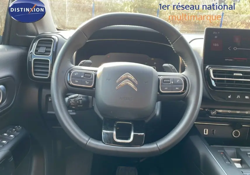 Vue intérieure centrée sur le volant noir du Citroën C5 Aircross 2025, avec tableau de bord et écran tactile visibles.